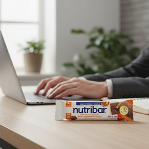 Person using a laptop with a Nutribar bar on a desk in a modern office setting