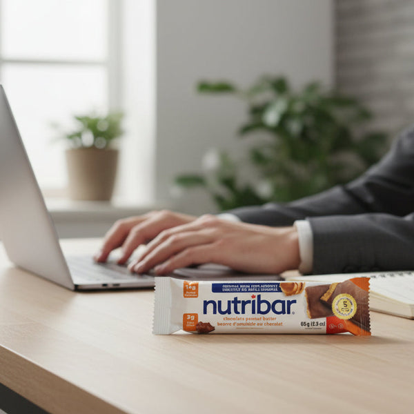Person using a laptop with a Nutribar bar on a desk in a modern office setting