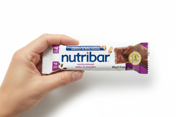 Hand holding a Nutribar mocha almond flavor bar on a white background